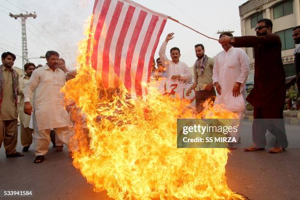 Pakistani demonstrator holds a burning US flag as others shout slogans during a protest in Multan on May 24 against a US drone strike in Pakistan's...