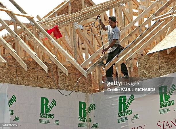 This 06 August, 2005 file photo shows a construction worker pulls his nail gun thru 2x4s that will be part of the roof of a single family home under...