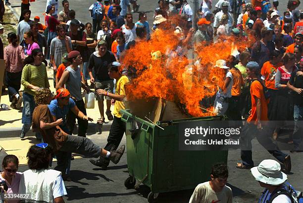 Militant Jewish settler extremists torch a garbage container during clashes with Israeli police who tried to secure the entry of shipping containers...