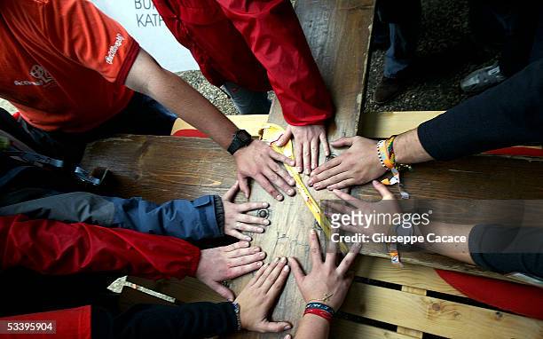 People put their hands on the Cross of the World Youth Day as it arrives in Cologne on August 16, 2005 in Cologne, Germany. Thousands of young...