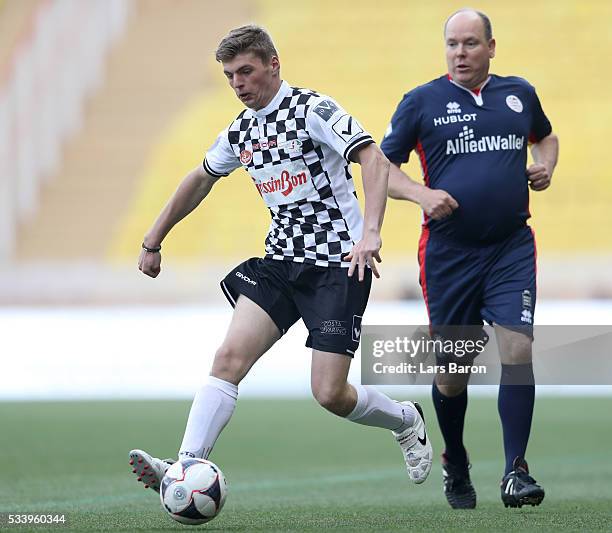 Max Verstappen of Netherlands and Red Bull Racing runs with the ball next to Prince Albert of Monaco during the 24th World Stars football match at...