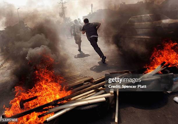 Teenagers run past a fire blockade erected in a stand off with police sent in to evacuate the Israeli settlement of Neve Dekalim in the Gush Katif...