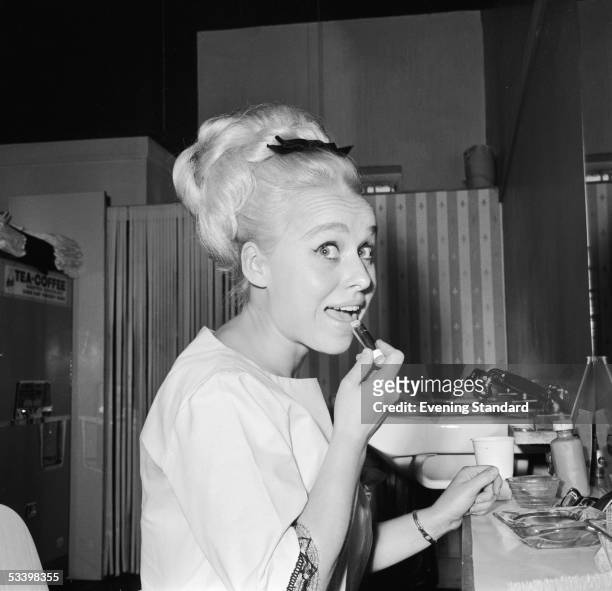 English actress Barbara Windsor puts on lipstick in her dressing room, 17th August 1964.
