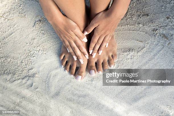 hands on bare feet on a white beach - womans bare feet fotografías e imágenes de stock