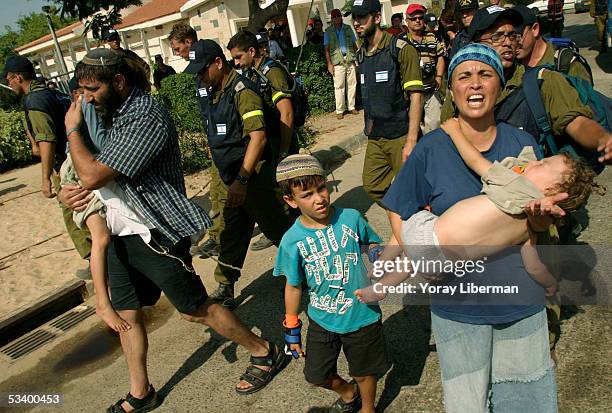 Settlers carry their children upon being evacuated from their homes August 17, 2005 in the Gaza Strip settlement of Neve Dekalim. Thousands of...