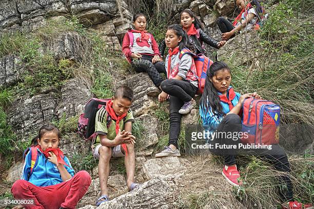 Children of Atule'er Village take a rest during climbing the cliff on their way home in Zhaojue county in southwest China's Sichuan province on May...