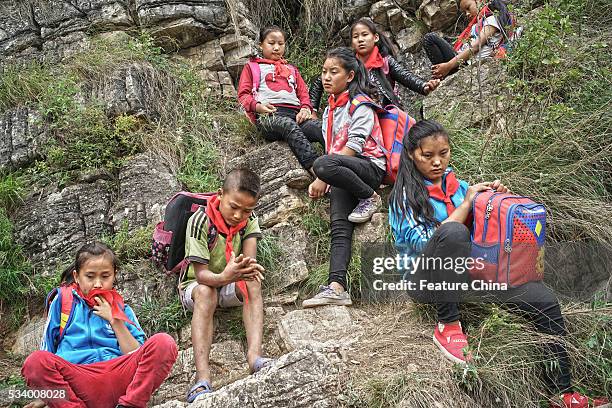 Children of Atule'er Village take a rest during climbing the cliff on their way home in Zhaojue county in southwest China's Sichuan province on May...