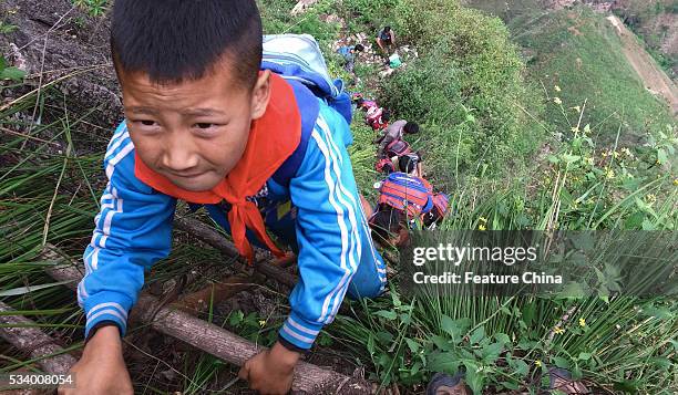 Children of Atule'er Village climb the vine ladder on a cliff on their way home in Zhaojue county in southwest China's Sichuan province on May 14,...