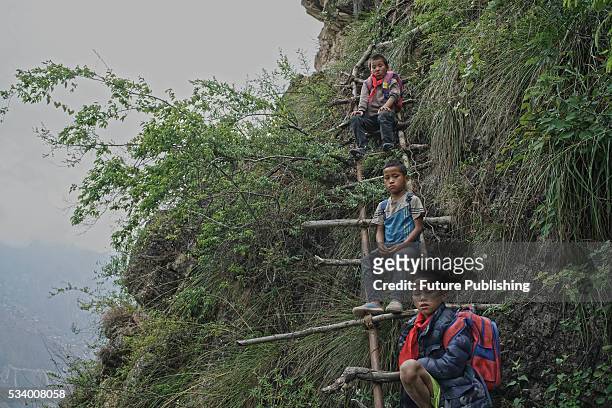 Children of Atule'er Village take a rest during climbing the vine ladder on a cliff on their way home in Zhaojue county in southwest China's Sichuan...