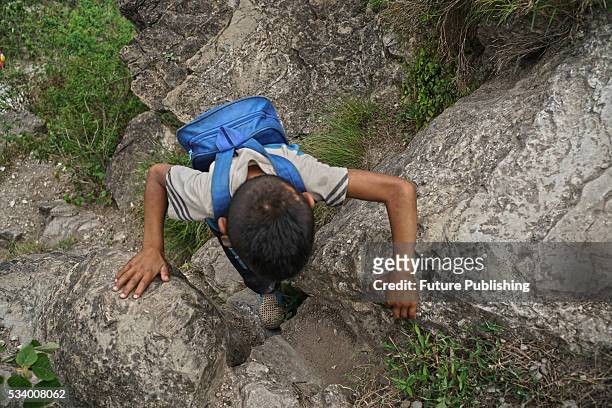 Boy of Atule'er Village climbs rock on his way home in Zhaojue county in southwest China's Sichuan province on May 14, 2016 in Zhaojue, China. There...