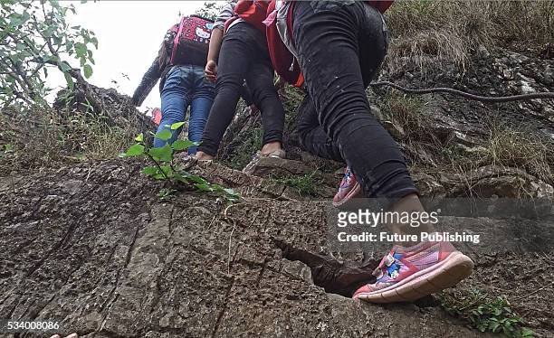 Children of Atule'er Village climb a cliff on their way home in Zhaojue county in southwest China's Sichuan province on May 14, 2016 in Zhaojue,...