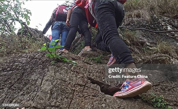 Children of Atule'er Village climb a cliff on their way home in Zhaojue county in southwest China's Sichuan province on May 14, 2016 in Zhaojue,...