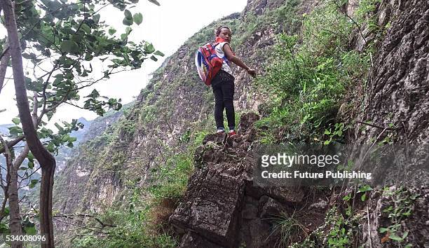 Girl of Atule'er Village looks back during climbing a cliff on her way home in Zhaojue county in southwest China's Sichuan province on May 14, 2016...