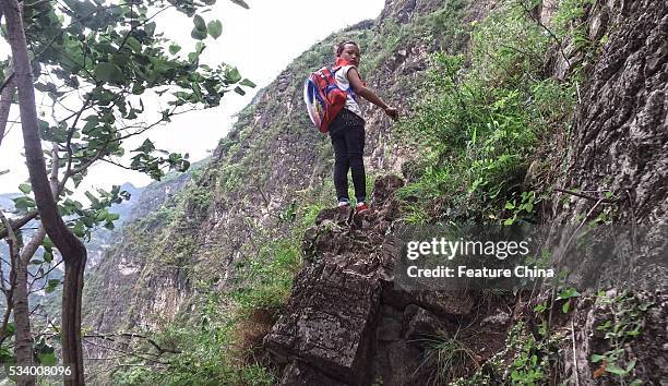 Girl of Atule'er Village looks back during climbing a cliff on her way home in Zhaojue county in southwest China's Sichuan province on May 14, 2016...