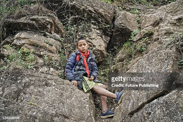 Boy of Atule'er Village takes a rest during climbing the a cliff on his way home in Zhaojue county in southwest China's Sichuan province on May 14,...