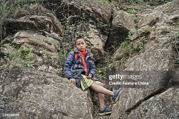 Boy of Atule'er Village takes a rest during climbing the a cliff on his way home in Zhaojue county in southwest China's Sichuan province on May 14,...