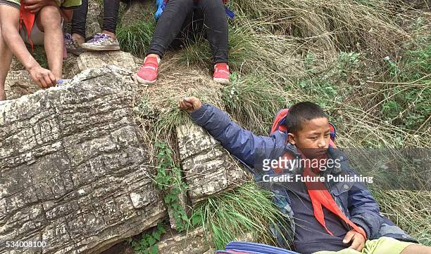 Children of Atule'er Village take a rest during climbing the cliff on their way home in Zhaojue county on May 14, 2016 in Zhaojue, China. There are...