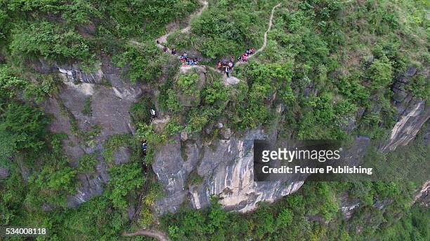 Children of Atule'er Village climb on the vine ladder on a cliff on their way home in Zhaojue county in southwest China's Sichuan province on May 14,...