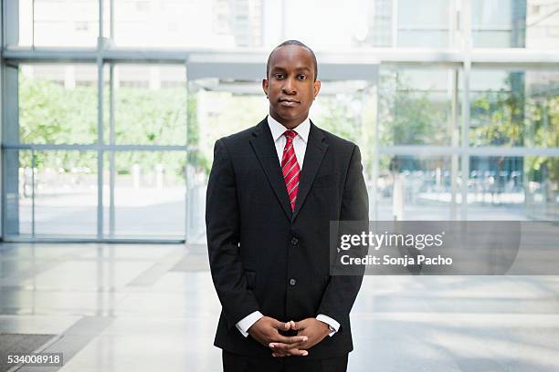 businessman standing in office building lobby - black suit stockfoto's en -beelden