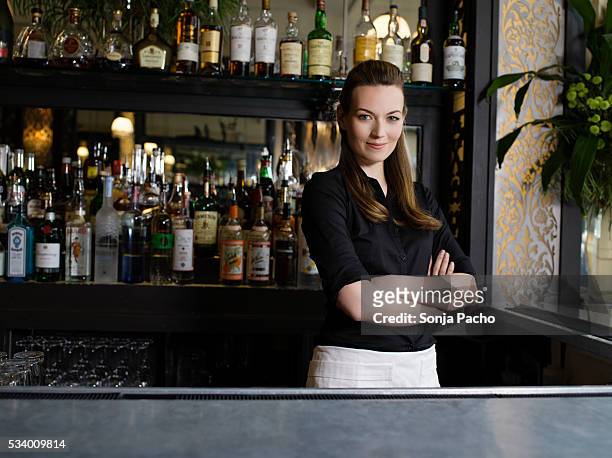 bartender standing behind bar - bartender stock pictures, royalty-free photos & images