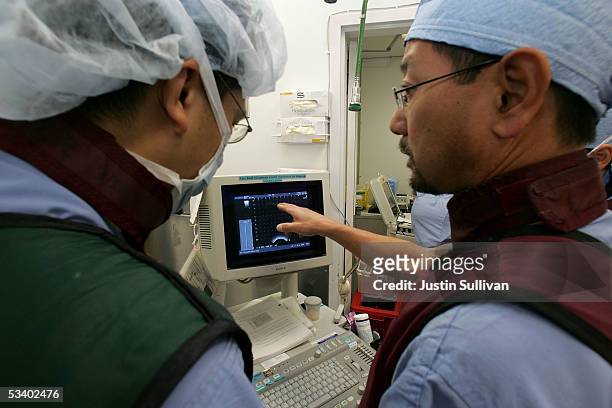 Dr. Katsuto Shinohara and Dr. Surat Dhonsombat look at a video monitor as they perform a bracytherapy operation on a man with prostate cancer at the...