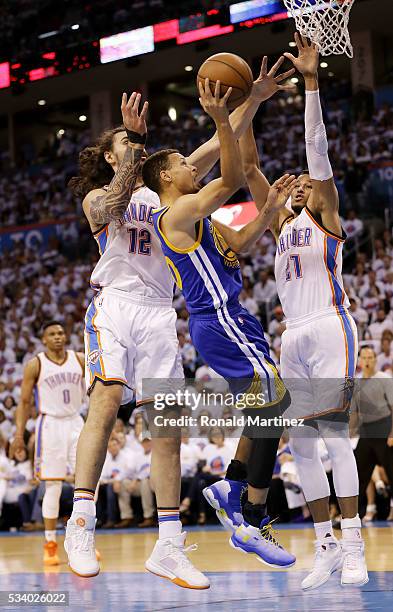 Stephen Curry of the Golden State Warriors goes up against Steven Adams and Andre Roberson of the Oklahoma City Thunder in the first quater in game...