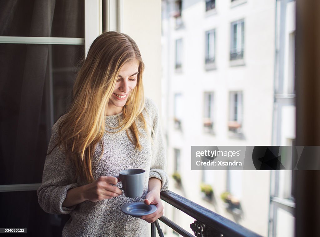 Frau trinkt Kaffee auf dem Balkon