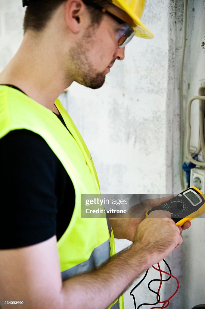 Electrician testing for voltage in a fuse box