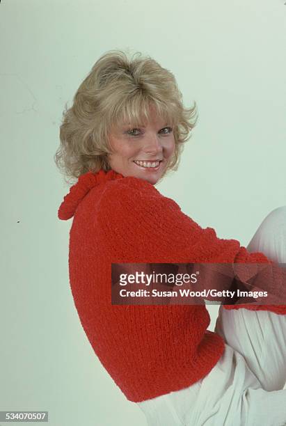 Portrait of American actress and television personality Cathy Lee Crosby as she poses in a red sweater and white trousers, July 1980.