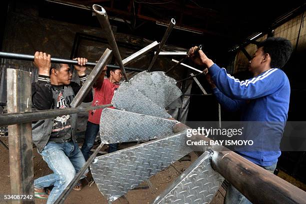 Workers weld pieces of a circular stairway together at a workshop in Jakarta on May 25, 2016. Indonesia has opened a string of new sectors to foreign...