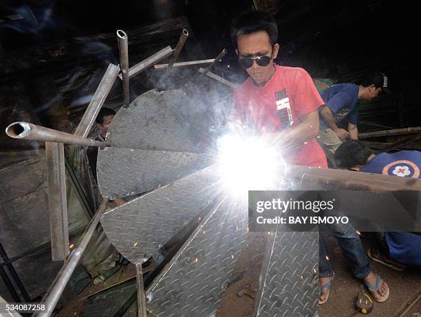 Man welds pieces of a circular stairway together at his workshop in Jakarta on May 25, 2016. Indonesia has opened a string of new sectors to foreign...