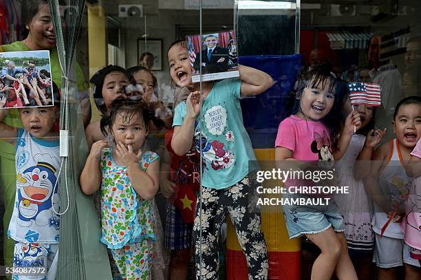 Children hold pictures of US President Barack Obama as people line up the streets to catch a glimpse of the US leader on his way to the airport at...