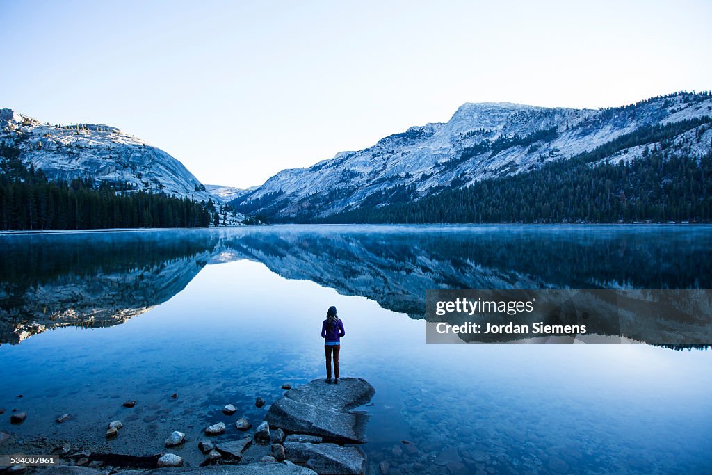 A woman watching the sunrise over a lake.