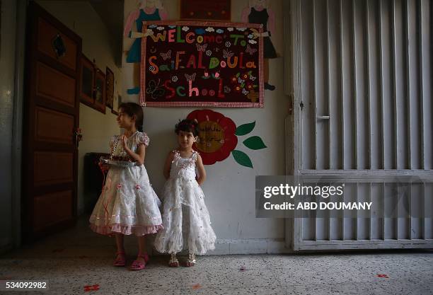Syrian school girls stand at the entrance of the Saif al-Dawla school as they take part in activities surrounding an art competition organised as...