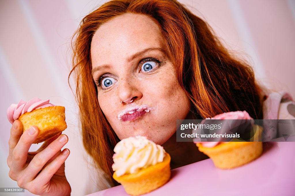 Jovem mulher comendo Cupcakes com muito entusiasmo
