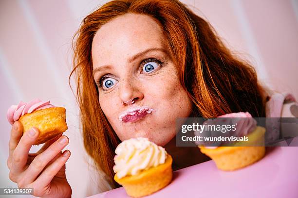 jovem mulher comer cupcakes com muito entusiasmo - cake face imagens e fotografias de stock