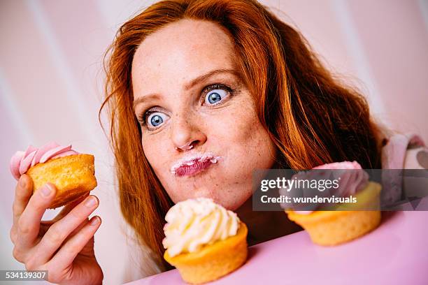 young woman eating cupcakes with a lot of enthusiasm - sugar food 個照片及圖片檔