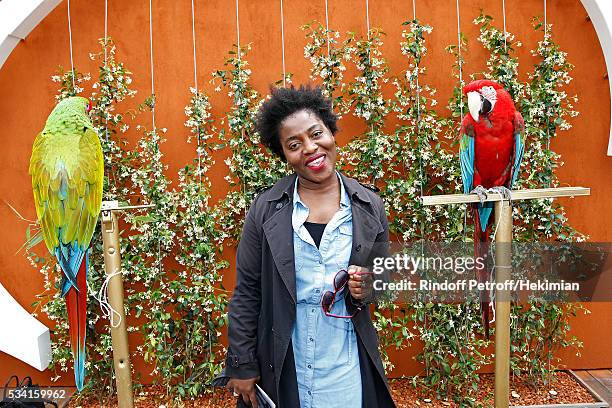 Humorist Claudia Tagbo standing between parrots Arthur and Zoe attend the 2016 French Tennis Open - Day Four at Roland Garros on May 25, 2016 in...
