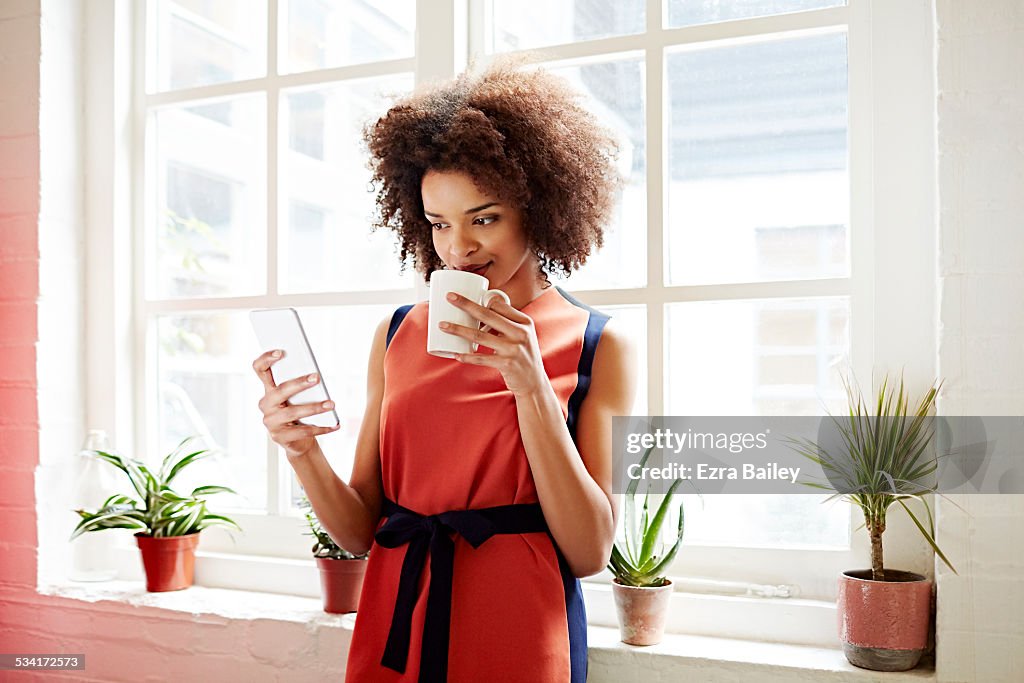 Woman drinking coffee and checking her phone