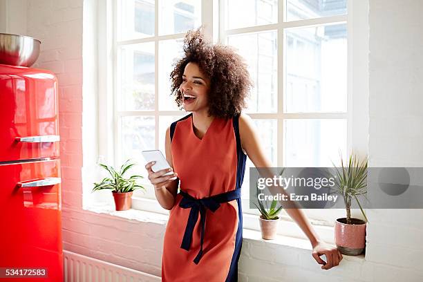 young woman laughing in a trendy apartment - wear red day - fotografias e filmes do acervo