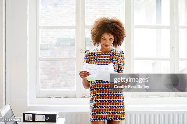 young mixed race woman looking through paperwork - portrait of cool creative businesswoman at office bildbanksfoton och bilder