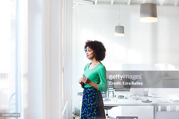 businesswoman staring out the window thinking. - luce vivida foto e immagini stock