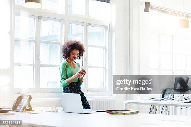 businesswoman using her phone in open plan office - grüne bluse stock-fotos und bilder