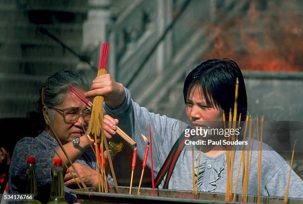 Two women burn incense sticks at a Buddhist temple in Hong Kong