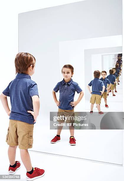 boy (4-5) looking into her reflections in mirror - repetición fotografías e imágenes de stock