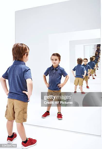 boy (4-5) looking into her reflections in mirror - multiplication photos et images de collection