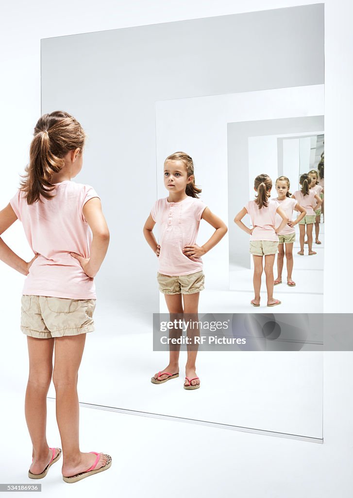 Girl (4-5) looking into her reflections in mirror