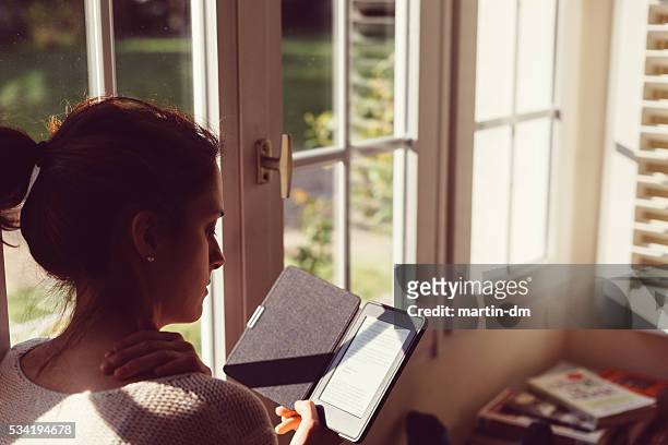 woman at home reading e-book - e reader stock pictures, royalty-free photos & images