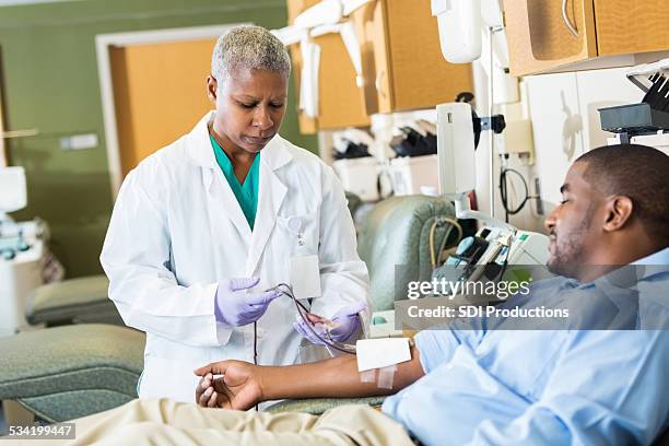 phlebotomist checking line whle patient donates blood in hospital - medical research blood stock pictures, royalty-free photos & images