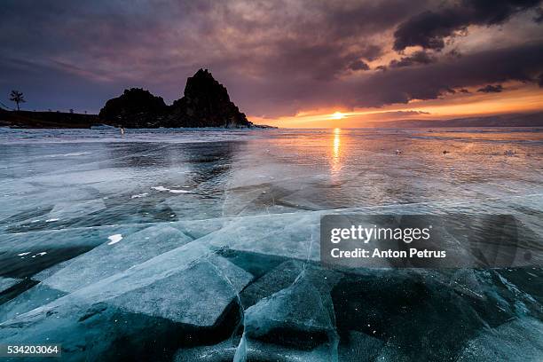sunset at the rock shamanka. lake baikal, winter - eisberg eisgebilde stock-fotos und bilder
